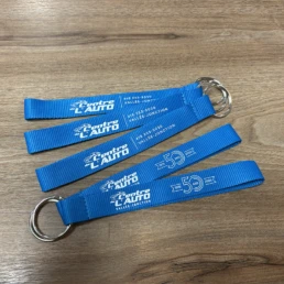 Quatre porte-clés bleus avec logos et numéro de téléphone.
